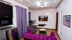莱基James Court Hotel & Luxury Apartments的客厅配有紫色沙发和电视