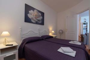 阿罗纳Cristianmar 3 - One Bed的一间卧室配有一张带紫色床单的床,墙上挂有一幅花卉画。