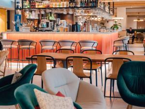 阿维尼翁Mercure Avignon Gare TGV的一间带桌椅的餐厅和一间酒吧