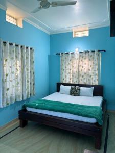 斋浦尔The Bainada farm的一间卧室配有一张带蓝色墙壁和窗帘的床