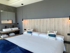 卡马里尼亚斯Hospedium Hotel Devalar Do Mar的卧室配有一张白色大床和两个水槽。