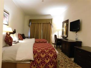 伊斯兰堡Islamabad Lodges的酒店客房配有一张床、一张书桌和一台电视。
