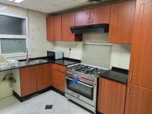 阿吉曼شقة فخمة وواسعة غرفتين luxury and big 2BR的厨房配有木制橱柜和炉灶烤箱。