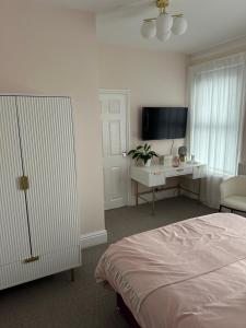曼彻斯特Room in Manchester的一间卧室配有一张床、一张书桌和一台电视