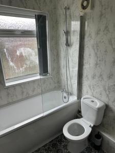 曼彻斯特Room in Manchester的一间带卫生间和浴缸的浴室以及窗户。
