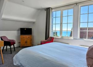 法尔茅斯The Westcott by the Sea - Just for Adults的一间卧室设有一张床、一台电视和窗户。