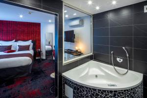 斯特拉斯堡Hôtel Garrigae Villa La Florangerie的带浴缸和床的酒店客房