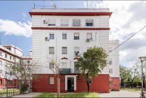 塞维利亚Acogedor y precioso apartamento en Sevilla的一座高大的白色建筑,有红色的地基