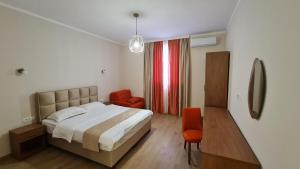 波德戈里察拉古纳酒店的一间卧室配有一张床和两张橙色椅子