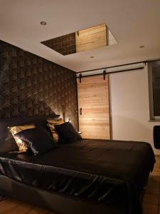 Flémalle-GrandeLes bulles d'or的一间卧室设有一张黑色的床和一扇木门。