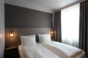 法尔肯堡单极大酒店的一间卧室配有一张带白色床单的床和一扇窗户。