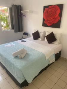 瓜鲁雅Hotel Iracemar - Piscina Aquecida的卧室配有一张大床,墙上挂着红玫瑰画