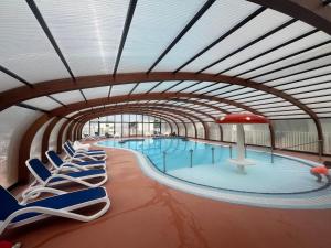 乌伊斯特勒昂Mobile-home Camping 4 etoiles bord de mer的大楼内带躺椅的大型游泳池
