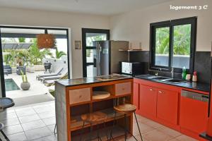 圣勒Loc974 Les Cocotiers的一间厨房,配有红色橱柜,享有庭院的景色