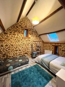 VautorteGîte l'étable détente的一间卧室设有两张床和石墙