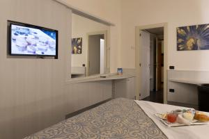 莱尼亚诺Hotel City Legnano的酒店客房设有一张床和墙上的电视