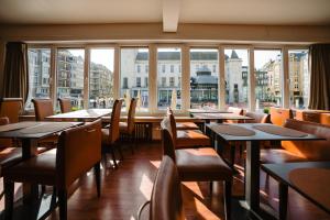 奥斯坦德艾姆巴萨德洛酒店的餐厅设有桌椅和大窗户。