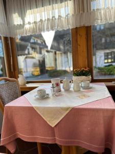 乌尔丁根-米赫尔霍芬Gästehaus Herzog的桌子上放着茶杯和碟子,还有窗户