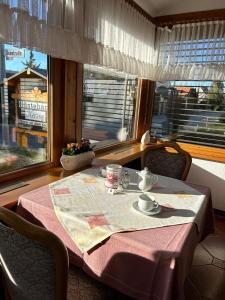 乌尔丁根-米赫尔霍芬Gästehaus Herzog的一张桌子,上面有粉红色的桌布和窗前的茶具