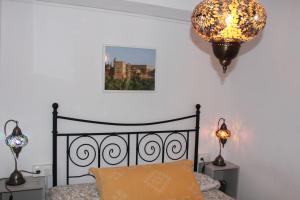 格拉纳达Apartamentos Vado - Cuesta de Alhacaba的一间卧室配有一张床和一个吊灯