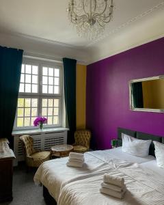 柏林安姆公园膳食旅馆的一间卧室设有紫色墙壁、两张床和吊灯。