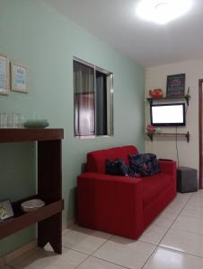 瓜拉派瑞Apt. de Setiba - HOSPEDARIA OCA RUCA的客厅设有一张红色沙发,配有电视