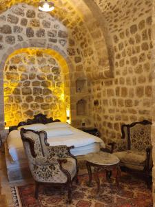 马尔丁Rumet paşa konağı的一间卧室,在石墙内配有床和椅子