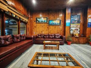 马拉里Surya International Hotel Manali near Mall Road的客厅配有棕色皮沙发和桌子