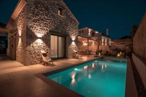 苏卡雷斯PAPADRIA VILLAS - Modern Luxury villas near Kathisma Beach的夜间带游泳池的别墅