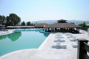 拉姆尼库沃尔恰Hotel Posada的一个带白色椅子和凉亭的游泳池