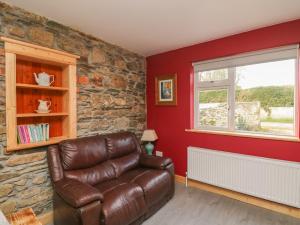 Curragh Cottage的客厅配有真皮沙发和窗户