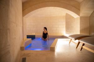 马泰拉Cenobio Hotel & SPA Matera的妇女在室内的热水浴缸中