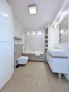 克拉科夫Turnau City Aparthotel的白色的浴室设有浴缸、卫生间和水槽。