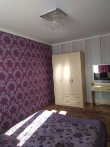 博斯特里Нур пансионат的卧室配有紫色壁纸、床和吊灯。