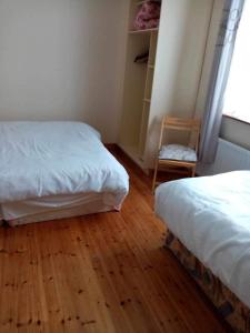 敦贝格Atlantic View的一间卧室设有两张床、一把椅子和一个窗户。