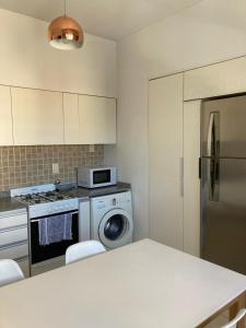 马德普拉塔Departamento en PLAYA GRANDE的厨房配有冰箱和洗衣机。