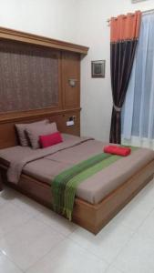 斯勒曼Sekar Wangi Homestay的一间卧室配有一张带红色和绿色枕头的大床