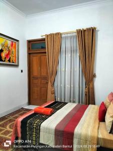 班图尔Pringgondani Homestay的一间卧室配有床和带窗帘的窗户