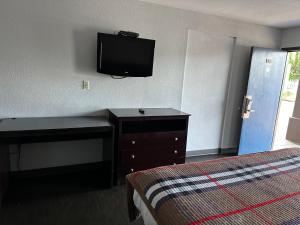 奥古斯塔Scottish Inn Augusta downtown的酒店客房配有一张床、一张书桌和一台电视。