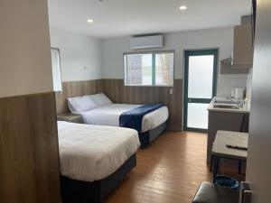 奥克兰Conway Motel Manukau的酒店客房带两张床和厨房