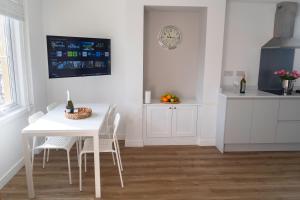 ClaypitsCrossways - Eastington的厨房配有白色的桌椅和时钟