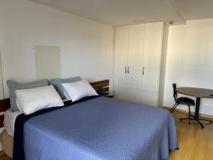 巴西利亚Flat Particular Hotel Saint Paul的一间卧室配有一张蓝色的床和一张桌子