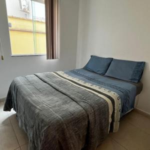里约达欧特拉斯Pousada Pé na Areia Rio das Ostras的一间卧室配有一张带蓝色枕头的床和一扇窗户。