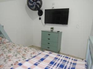 瓜鲁柳斯AEROHOSTEL Brasil的一间卧室配有一张床,墙上配有电视