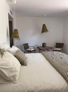 孔卡Casa Suvara - Chambres d'hôtes de charme I Piscines ou SPA privatifs的卧室配有一张带椅子的白色大床