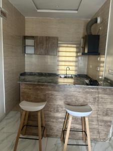 阿布贾Checkers Suite & Apartments的厨房配有2张凳子和带水槽的台面
