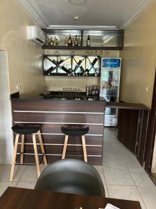 阿布贾Checkers Suite & Apartments的餐厅内的酒吧,设有2张凳子和1台冰箱