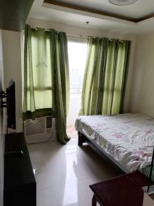 马尼拉Robinson manila birchtower的一间卧室设有床铺和一个带绿色窗帘的窗户。