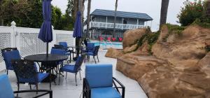皮斯莫比奇The Grove at Pismo Beach的一个带蓝色桌椅的庭院和一个游泳池