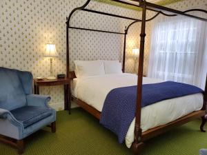 Northeast HarborHarbourside Inn的一间卧室配有天蓬床和蓝椅